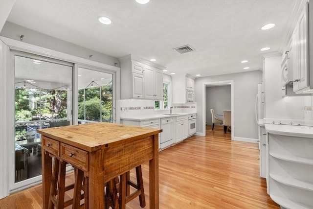 1 Pleasantview Ter, Framingham, MA 01701 - kitchen featuring light countertops, white appliances, white cabinets, light wood finished floors, and backsplash