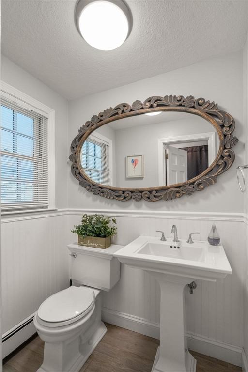 1 Pleasantview Ter, Framingham, MA 01701 - bathroom featuring a baseboard heating unit, a textured ceiling, wood finished floors, a wainscoted wall, and toilet