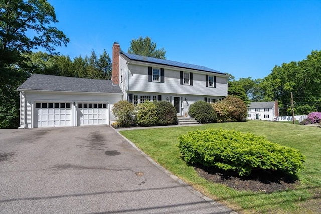 1 Pleasantview Ter, Framingham, MA 01701 - colonial inspired home featuring a chimney, roof mounted solar panels, a front yard, and asphalt driveway