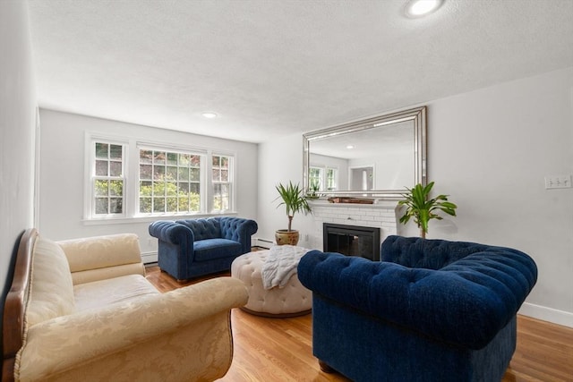 1 Pleasantview Ter, Framingham, MA 01701 - living area featuring a fireplace, wood finished floors, a textured ceiling, baseboard heating, and a baseboard radiator