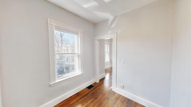 empty room featuring plenty of natural light and dark wood-type flooring