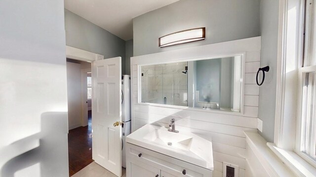 bathroom featuring vanity and a shower with door