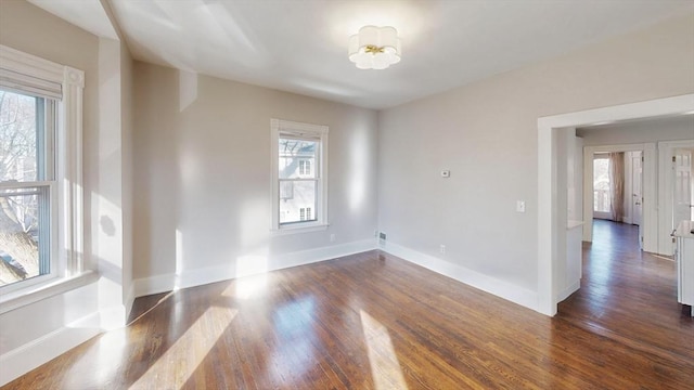 spare room with dark hardwood / wood-style flooring and a healthy amount of sunlight