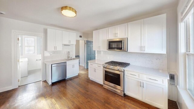 kitchen with decorative backsplash, appliances with stainless steel finishes, dark hardwood / wood-style flooring, sink, and white cabinets