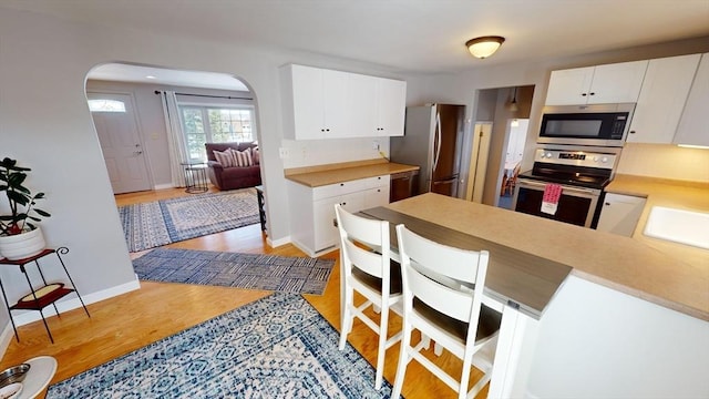 kitchen featuring white cabinetry, appliances with stainless steel finishes, kitchen peninsula, and light wood-type flooring