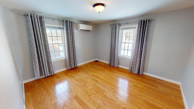 unfurnished room featuring a wall mounted air conditioner, hardwood / wood-style flooring, and plenty of natural light