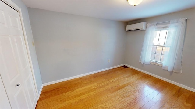 empty room with light hardwood / wood-style floors and a wall unit AC