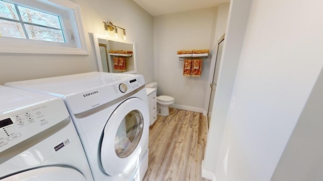 laundry room with washing machine and clothes dryer and light wood-type flooring