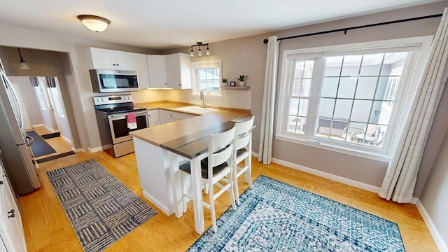 kitchen with white cabinetry, appliances with stainless steel finishes, sink, and light hardwood / wood-style flooring