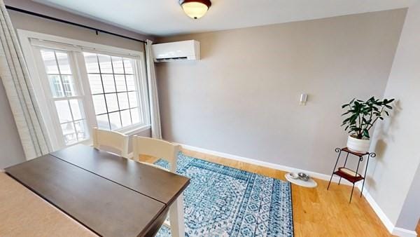 dining area with a wall mounted air conditioner and hardwood / wood-style floors