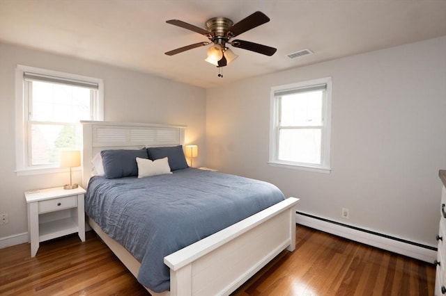 bedroom with visible vents, wood finished floors, baseboard heating, and multiple windows
