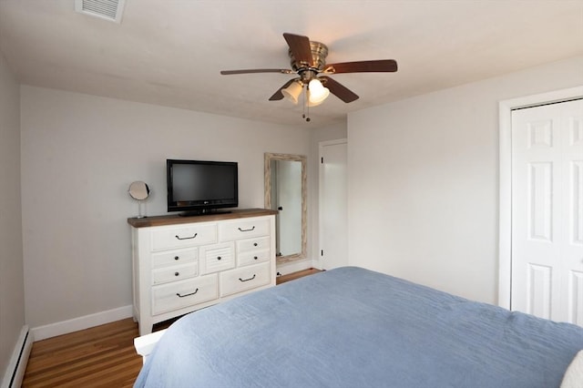 bedroom featuring ceiling fan, visible vents, baseboards, wood finished floors, and a baseboard heating unit