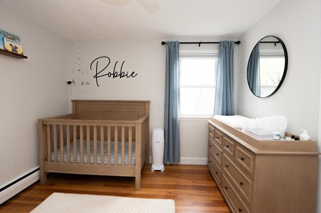 bedroom featuring baseboards, wood finished floors, and baseboard heating