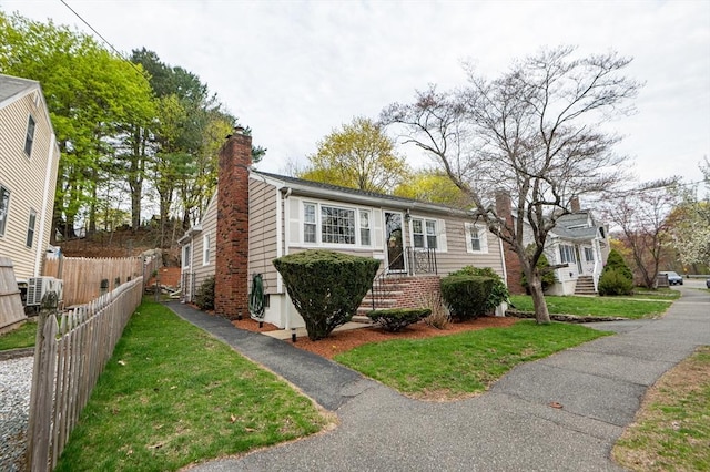 view of front of house with fence, a chimney, and a front lawn