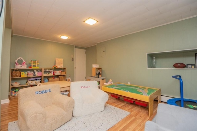 game room with crown molding, baseboard heating, and wood finished floors