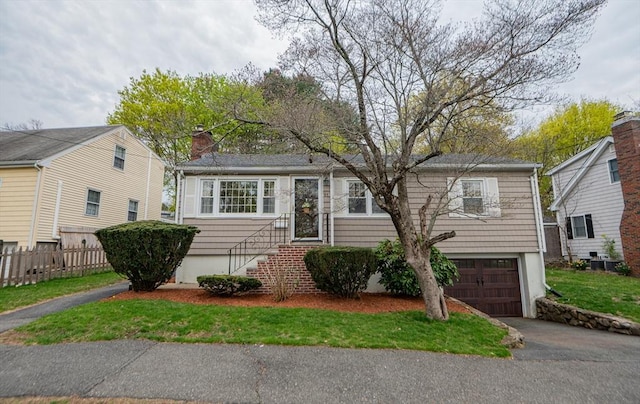 view of front of house with fence, an attached garage, a chimney, and aphalt driveway