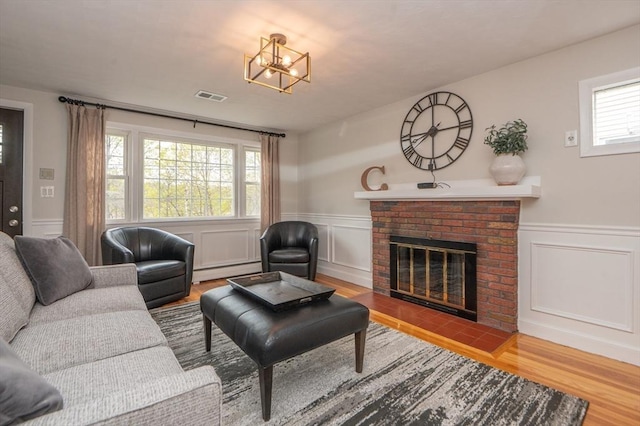 living area featuring visible vents, wainscoting, wood finished floors, and baseboard heating