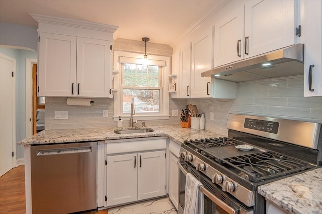 kitchen with light stone countertops, white cabinetry, under cabinet range hood, a sink, and stainless steel appliances
