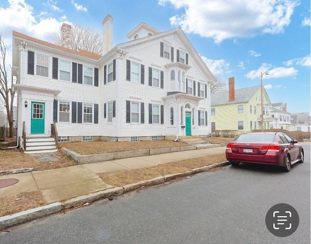 view of front of house featuring aphalt driveway, entry steps, and a chimney