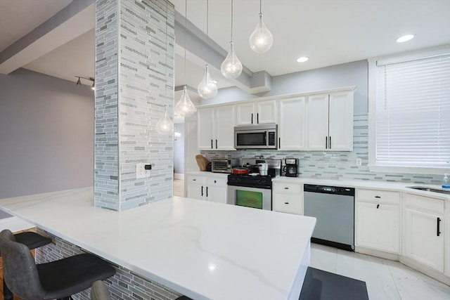 kitchen featuring a kitchen breakfast bar, white cabinetry, appliances with stainless steel finishes, decorative backsplash, and hanging light fixtures