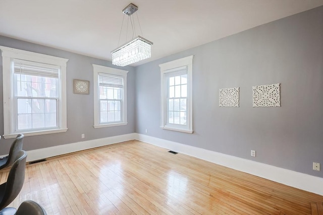 unfurnished dining area with visible vents, baseboards, and hardwood / wood-style flooring