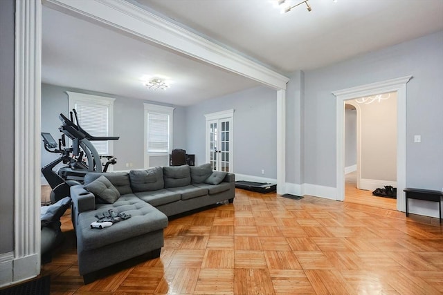 living room featuring baseboards, arched walkways, and french doors