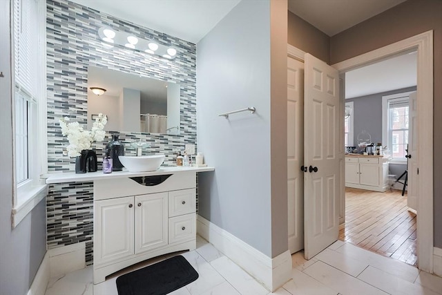 bathroom featuring vanity, baseboards, and backsplash