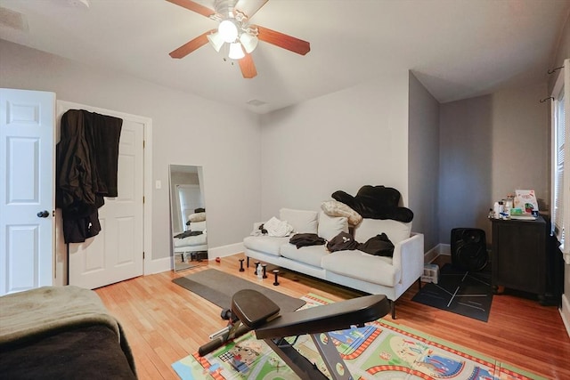 living room featuring ceiling fan, baseboards, and wood finished floors