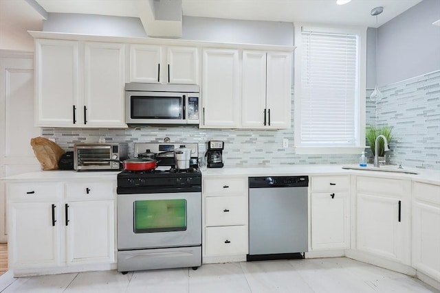 kitchen featuring a sink, backsplash, white cabinetry, stainless steel appliances, and light countertops