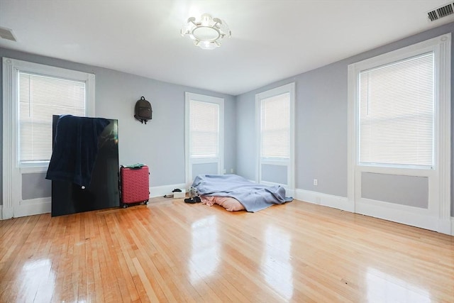 bedroom with hardwood / wood-style floors, multiple windows, and visible vents