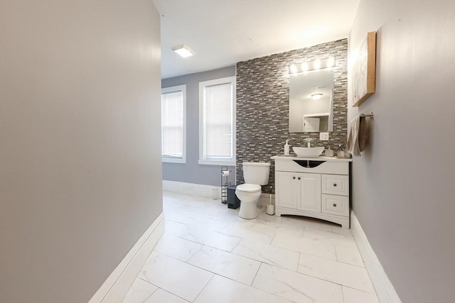 bathroom with vanity, toilet, baseboards, and marble finish floor