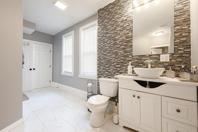 bathroom featuring visible vents, baseboards, toilet, marble finish floor, and vanity