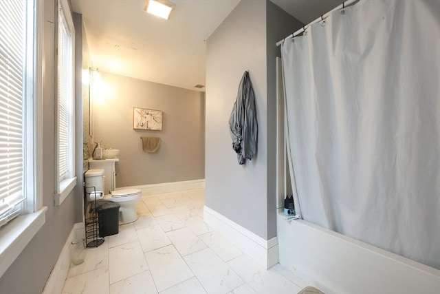 full bath featuring toilet, baseboards, marble finish floor, and shower / tub combo with curtain