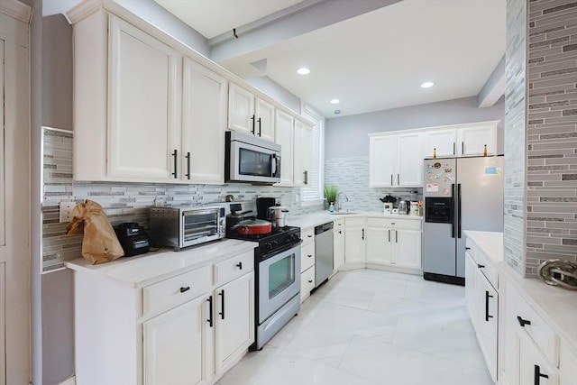 kitchen featuring stainless steel appliances, backsplash, white cabinets, and light countertops