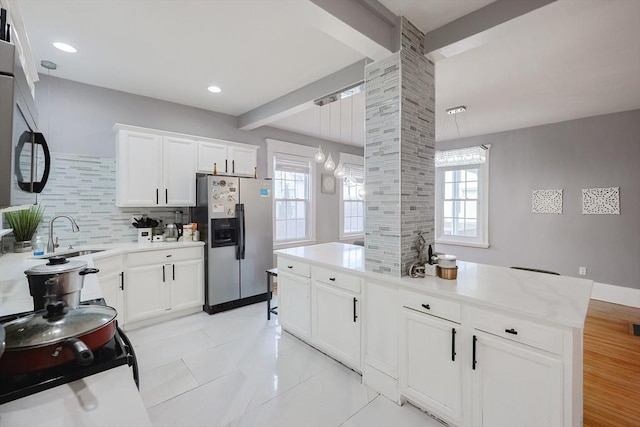 kitchen featuring beam ceiling, a sink, decorative backsplash, white cabinets, and stainless steel fridge