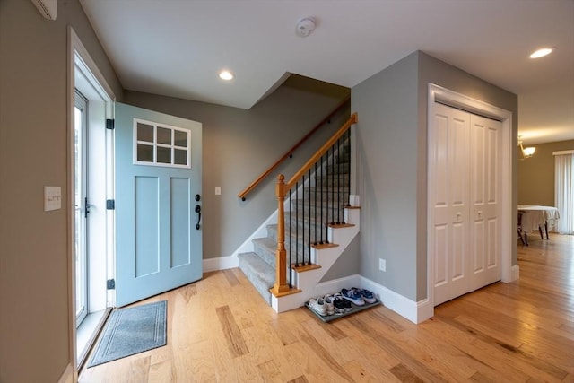 entrance foyer with a wall mounted air conditioner, a notable chandelier, and light hardwood / wood-style floors