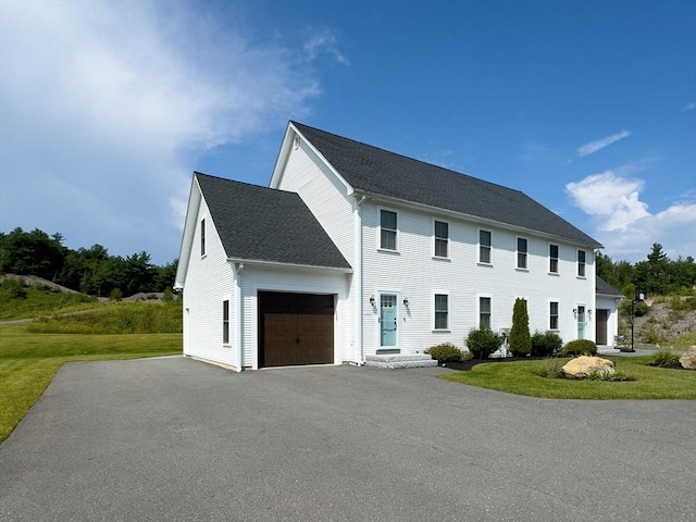 colonial inspired home featuring a front lawn and a garage