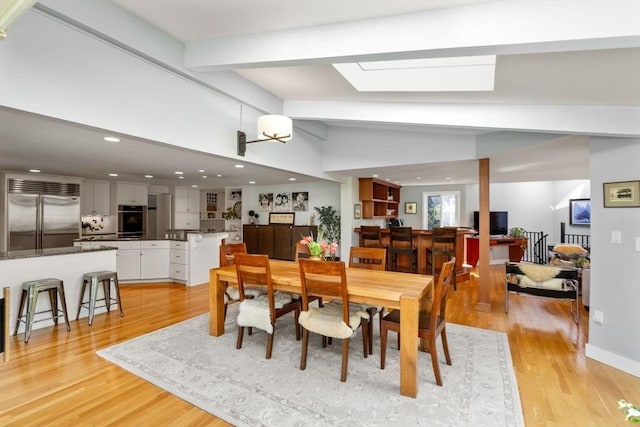 dining space featuring light wood-style flooring, a skylight, and recessed lighting