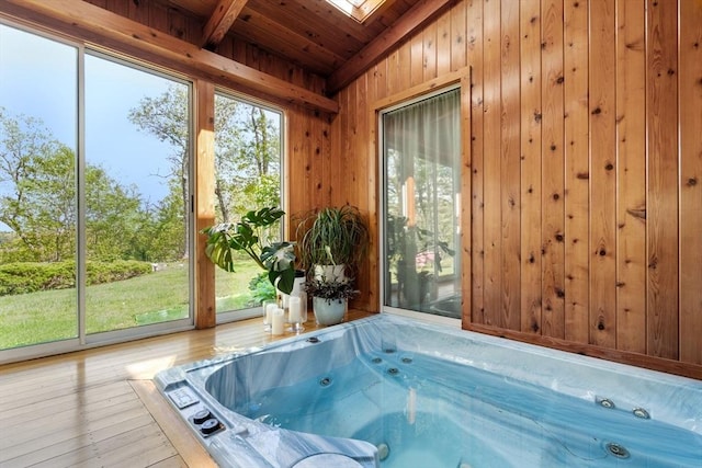 sunroom featuring a hot tub, vaulted ceiling, and a skylight