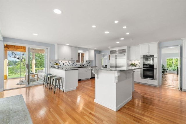 kitchen with stainless steel appliances, a breakfast bar, recessed lighting, and plenty of natural light