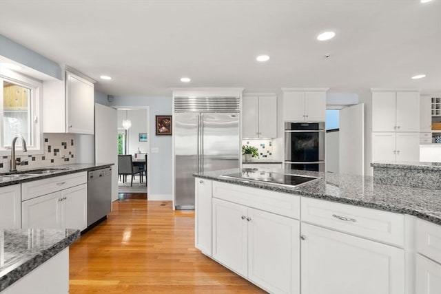 kitchen featuring appliances with stainless steel finishes, a sink, white cabinetry, tasteful backsplash, and recessed lighting