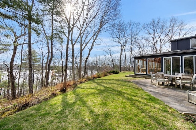 view of grassy yard with a sunroom and a patio