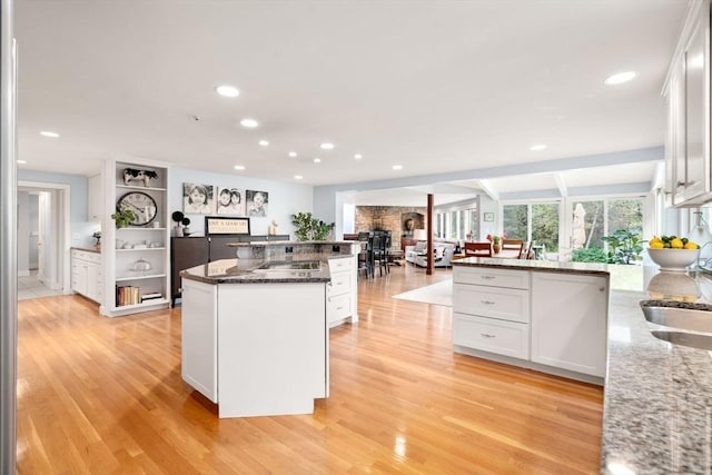 kitchen with recessed lighting, white cabinetry, light wood finished floors, and dark stone counters