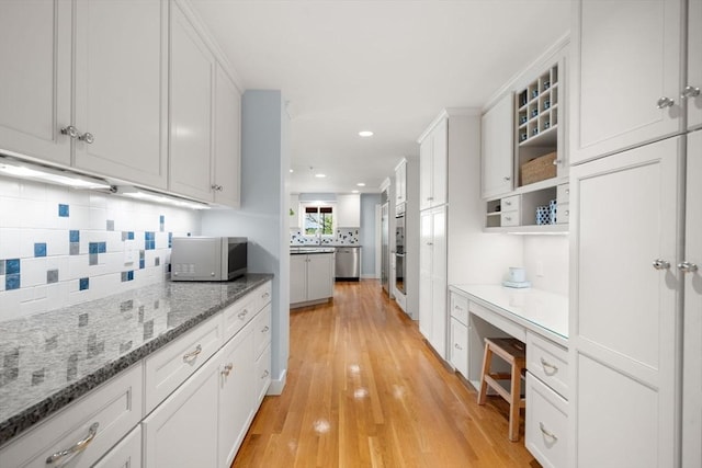 kitchen featuring white microwave, tasteful backsplash, white cabinets, light wood-style flooring, and recessed lighting