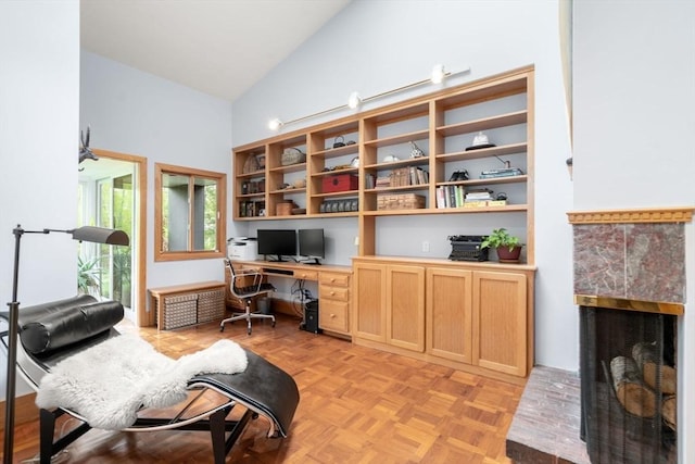 office area featuring high vaulted ceiling, built in desk, and a fireplace