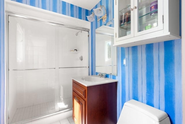 bathroom featuring a shower stall, wallpapered walls, vanity, and toilet