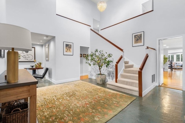 foyer entrance featuring stairway, baseboards, a high ceiling, recessed lighting, and a chandelier
