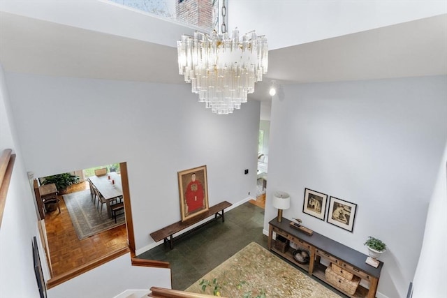 stairs featuring a chandelier, a high ceiling, and baseboards