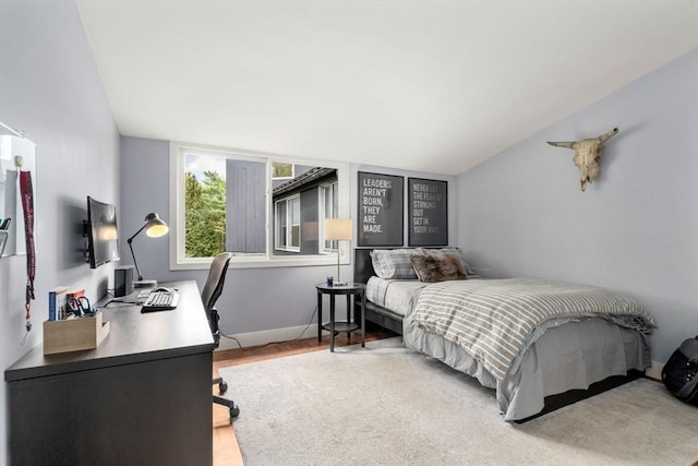 bedroom featuring an office area, lofted ceiling, wood finished floors, and baseboards