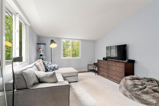 living room featuring plenty of natural light, lofted ceiling, light carpet, and baseboards